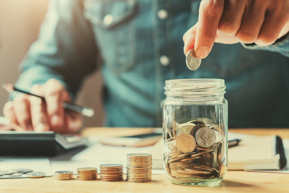 businessman holding coins putting in glass