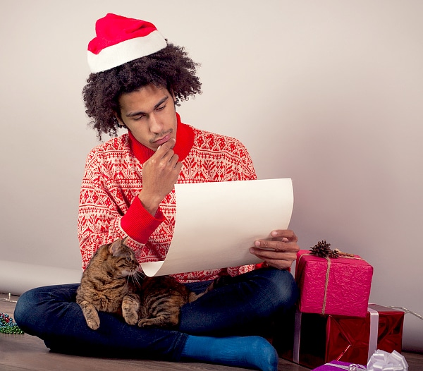A man looks at his holiday list while wrapping gifts. 