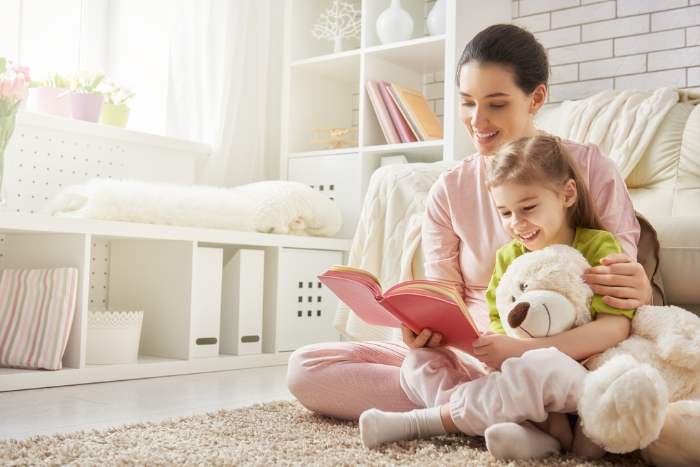 pretty young mother reading a book to her daughter