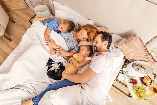 A family in bed with their cat.