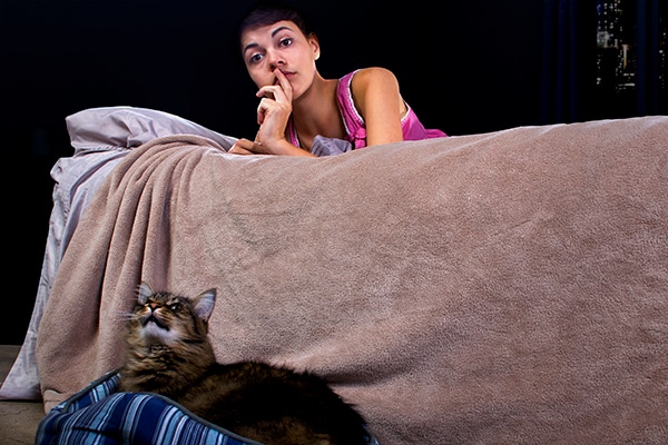 A woman shushing a cat meowing at night. 