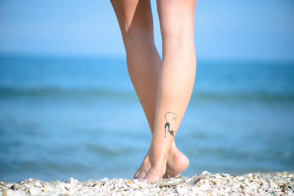 A girl with a cat tattoo on the beach.