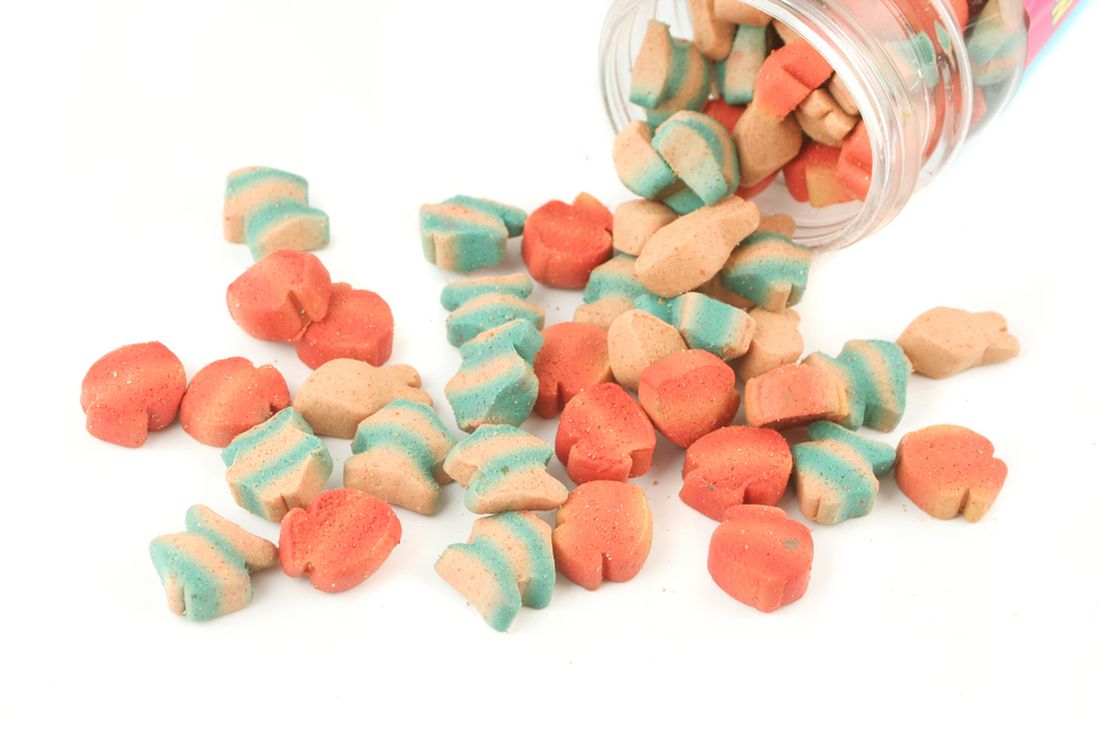 different colored fish shaped cat treats spilling from jar