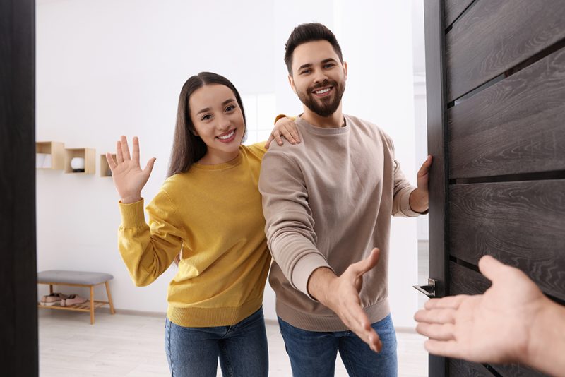 happy couple welcoming guest in their home