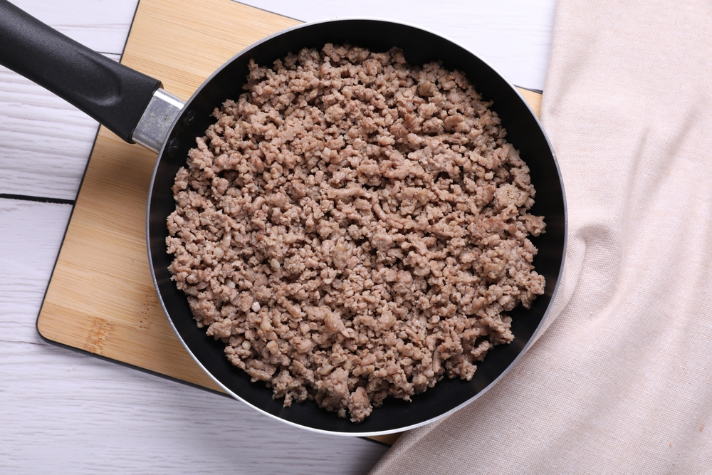 Fried minced meat in pan on white wooden table