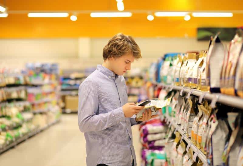 Man shopping in supermarket reading product information