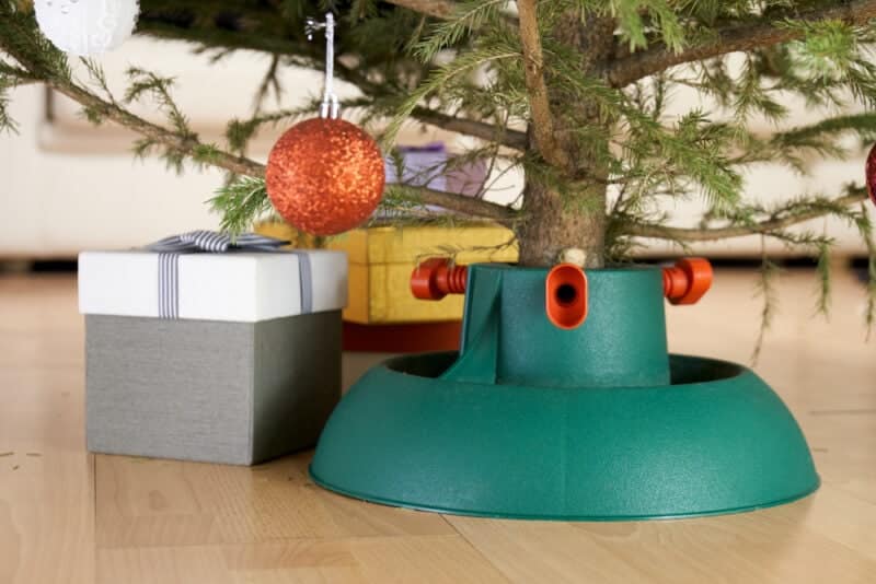 Plastic Christmas tree stand surrounded by gift boxes stands