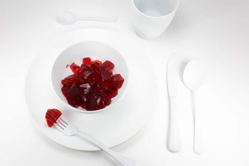 Red diced jello in a small white bowl