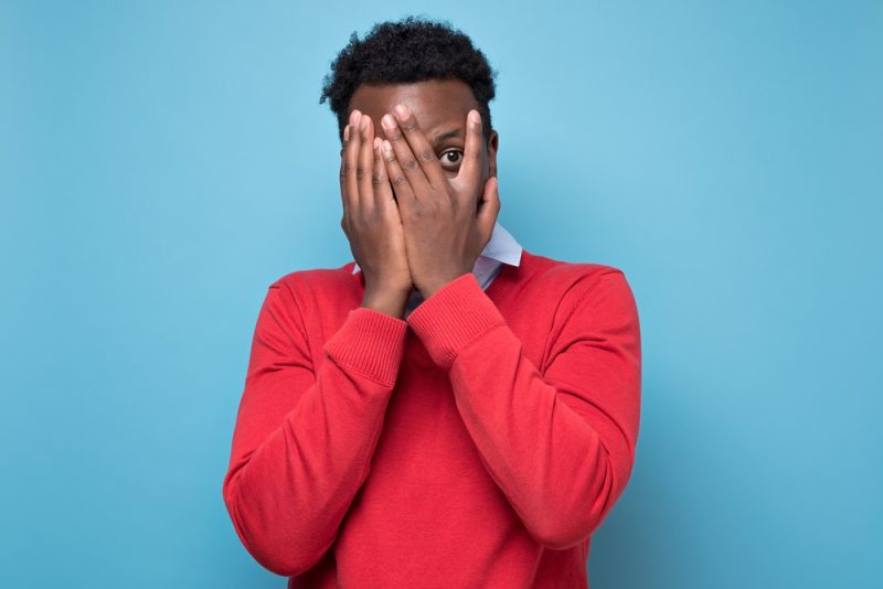 Scared man covering his face