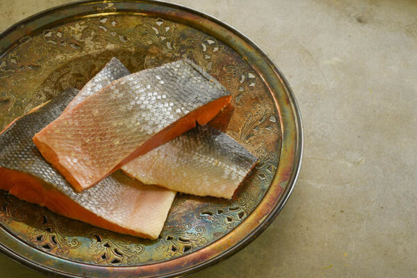 Wild sockeye salmon fillets on an ornate vintage silver plate