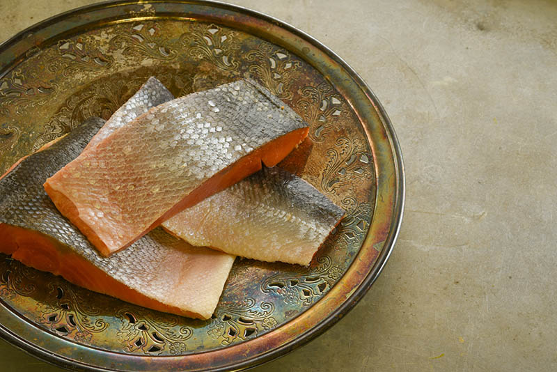 Wild sockeye salmon fillets on an ornate vintage silver plate