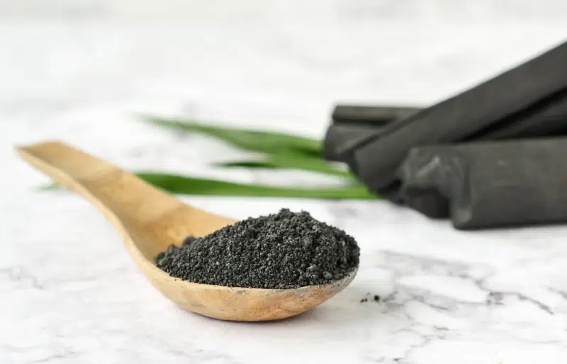 activated charcoal on wooden spoon on marble table