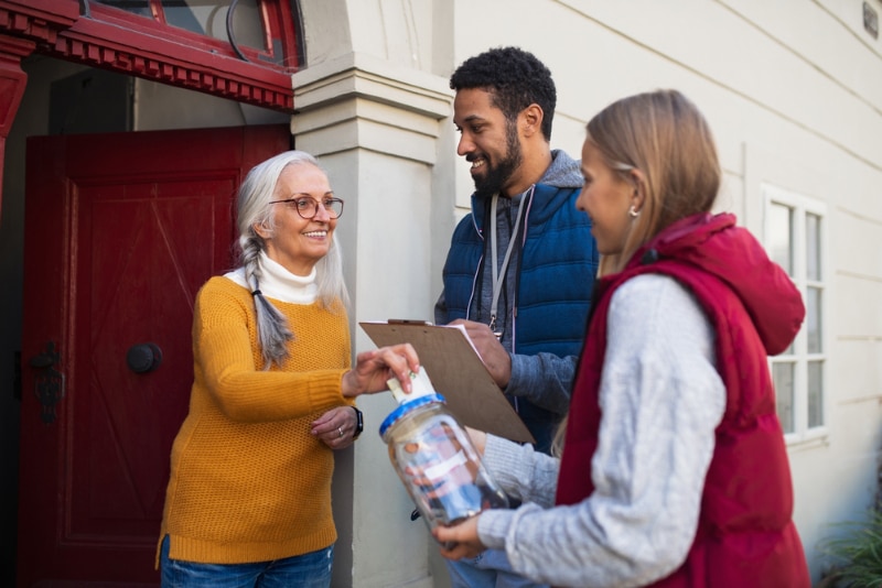 door to door fundraisers talking to senior woman and collecting money