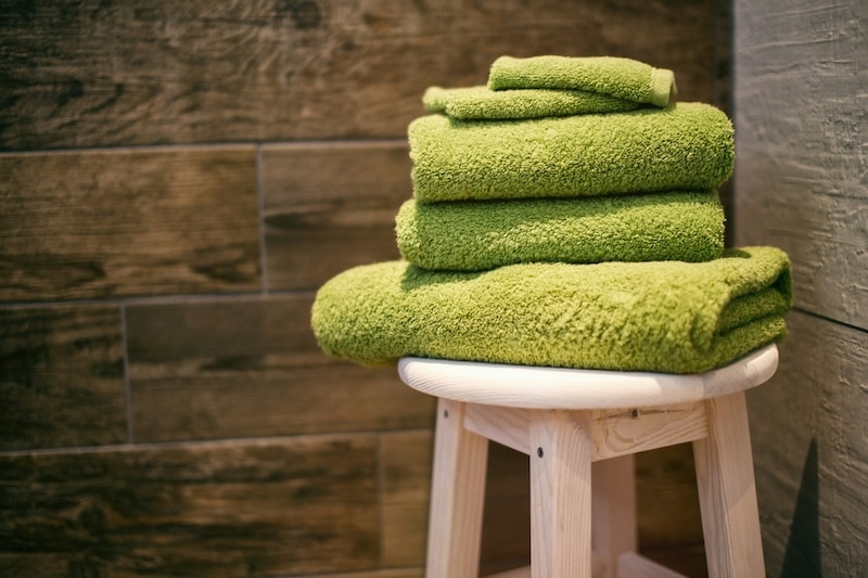 folded green towels on bathroom stool