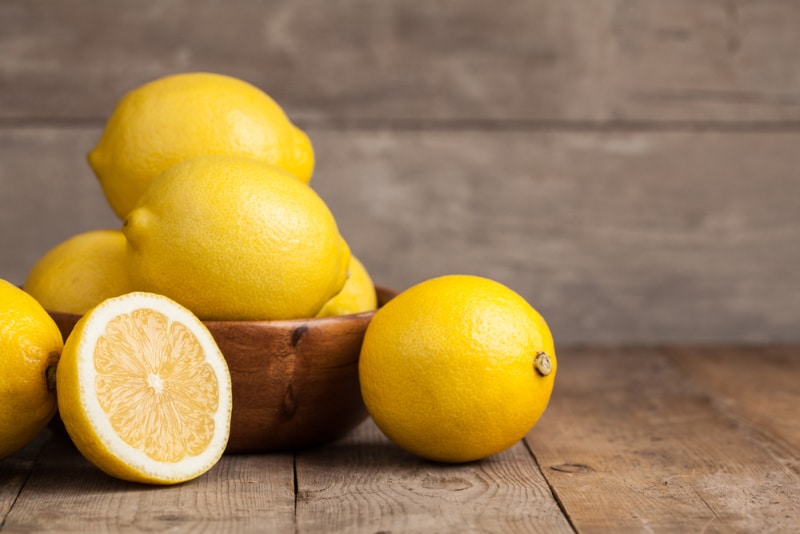 fresh lemons in the bowl and on the wooden table