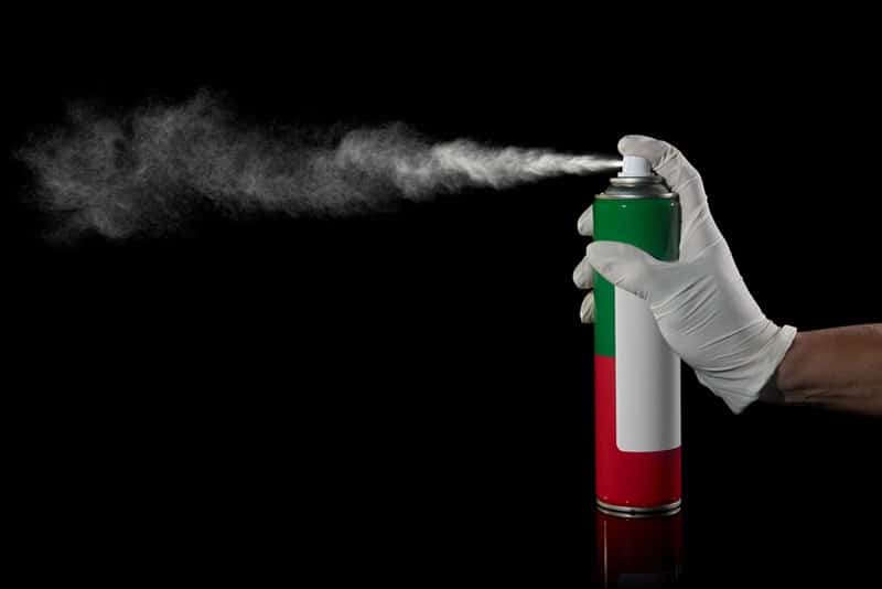 hand with gloves spraying a can of insecticide
