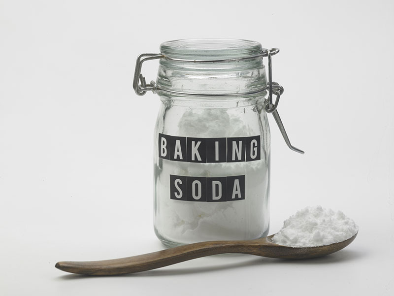 jar of baking soda and spoon on white background
