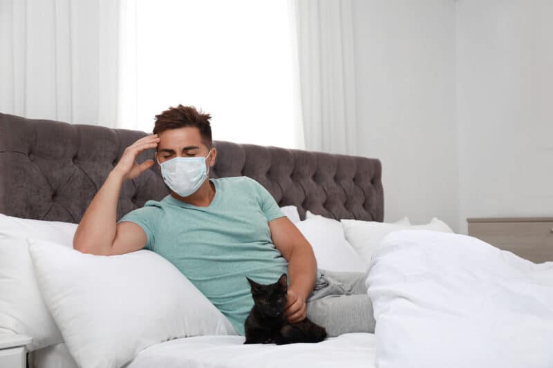 man sick with cat beside him