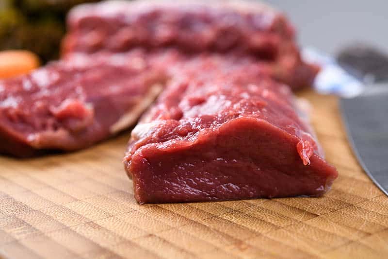 saddle of venison on wooden board with big knife