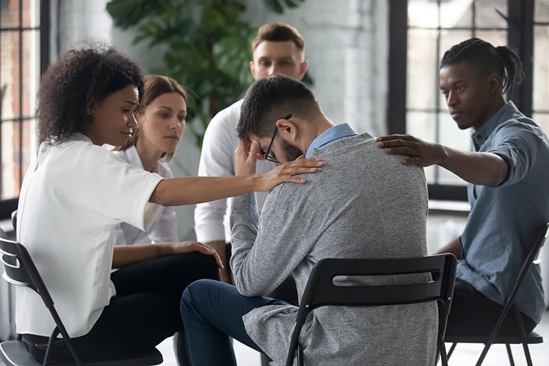 support group comforting a grieving young man