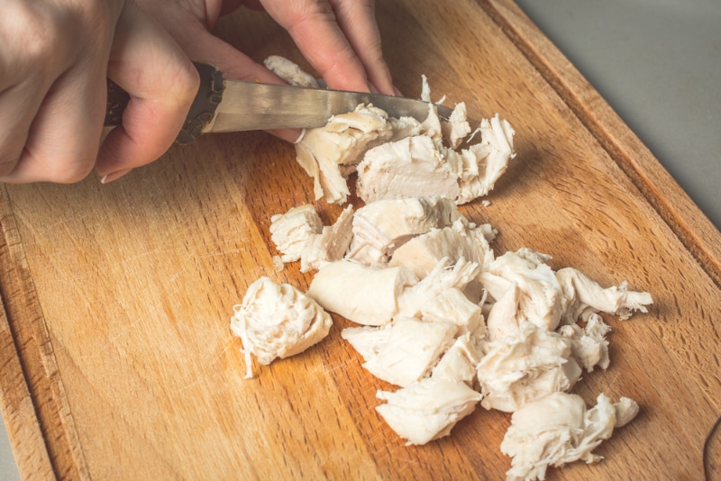 woman cutting boiled chicken breast