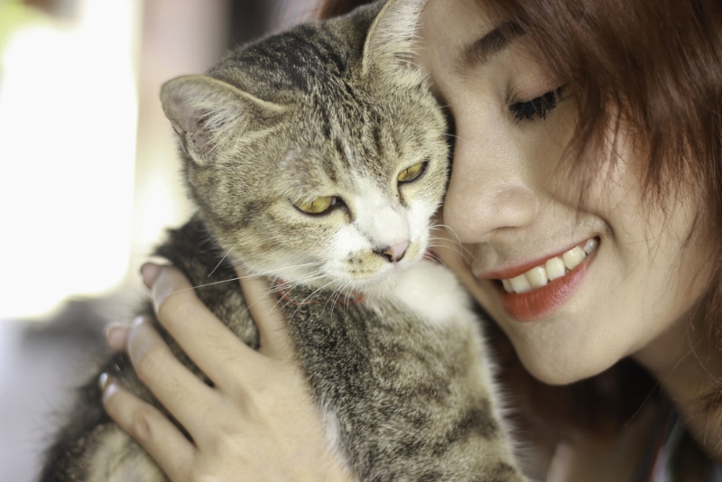 woman hugging her cat at home