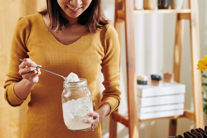 woman in a yellow sweater with jar of baking soda