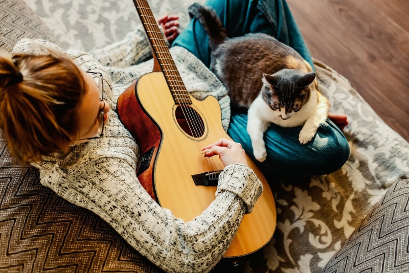 woman playing guitar with cat on her lap