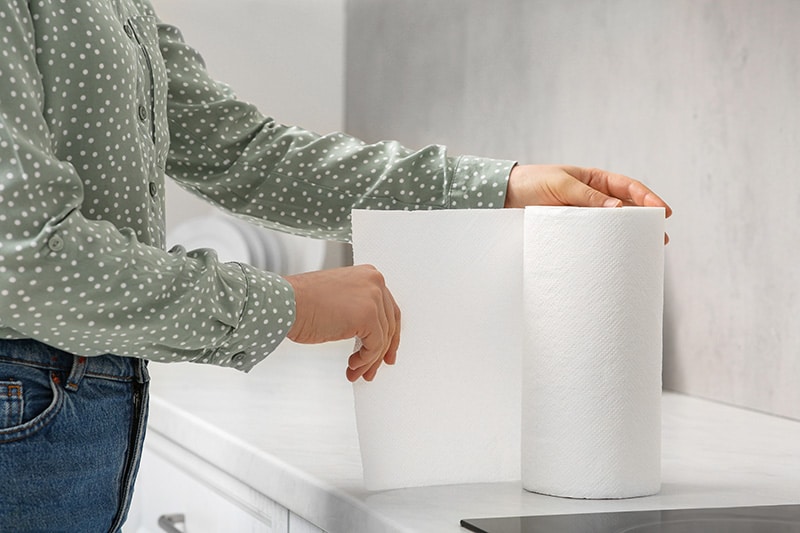 Woman tearing paper towels in kitchen