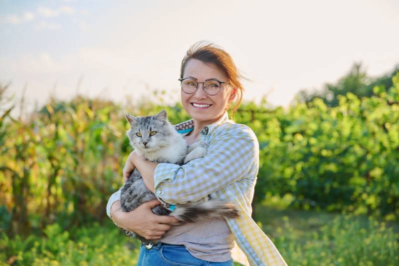 young womn carrying her cat outdoors