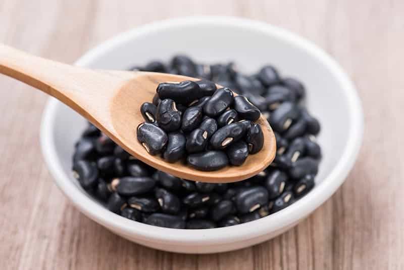 Black Beans in wooden spoon with ceramic bowl