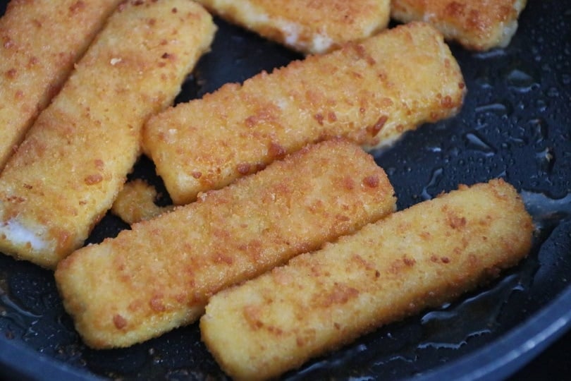 Fried fish sticks in a black pan