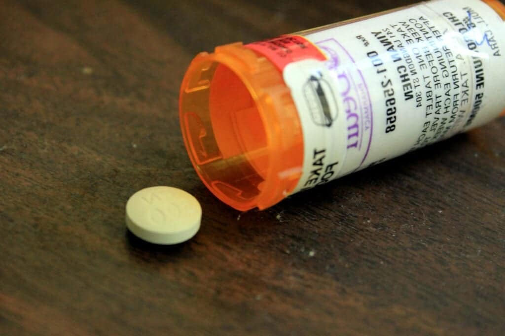 medicine tablet and container on a wooden surface