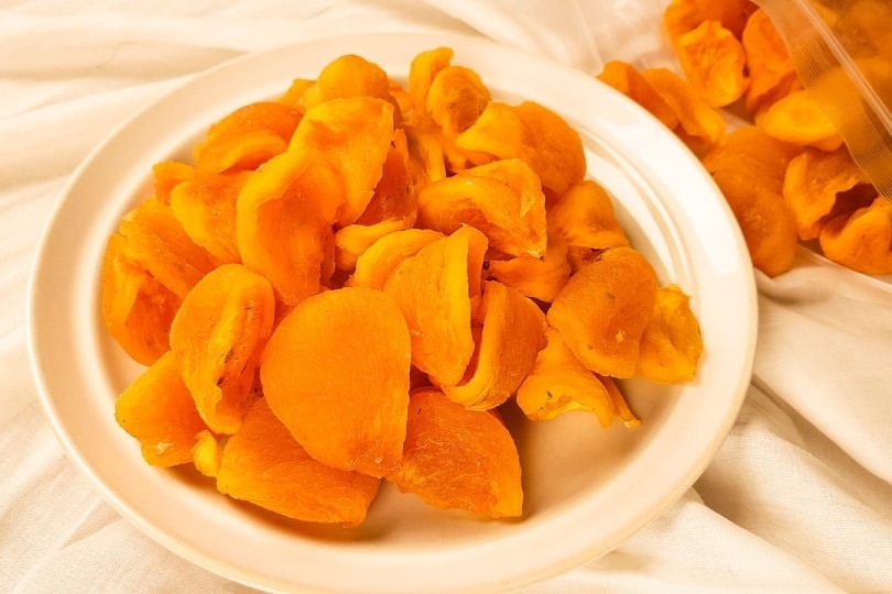 Peeled and pitted persimmon fruit in a plate