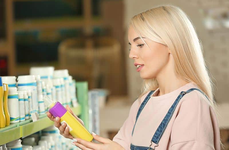 Pretty-young-woman-selecting-animal-shampoo-in-pet-shop