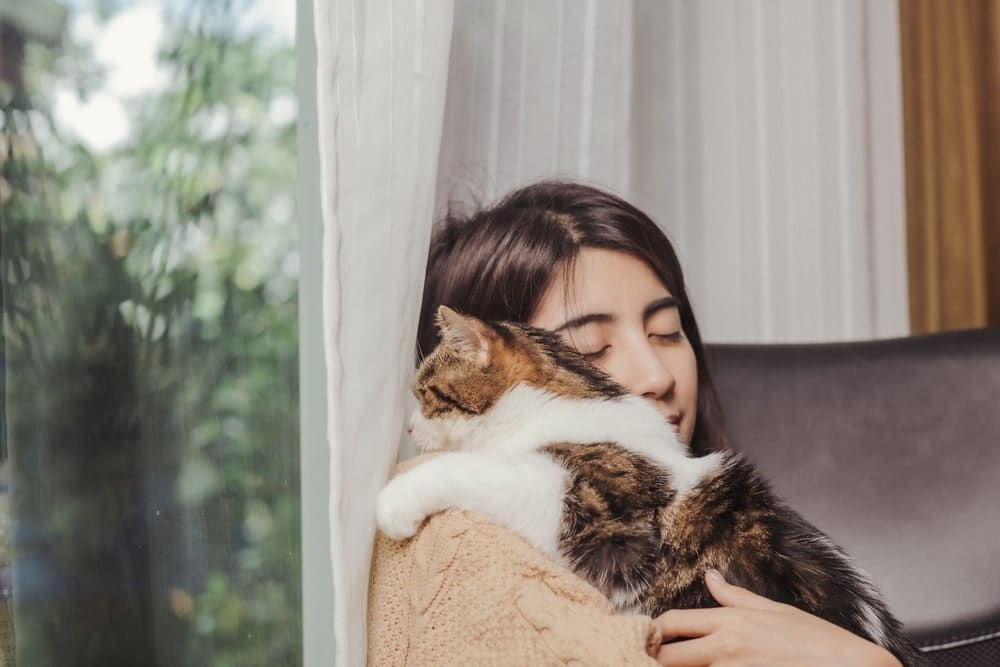 Woman owner hugging cat