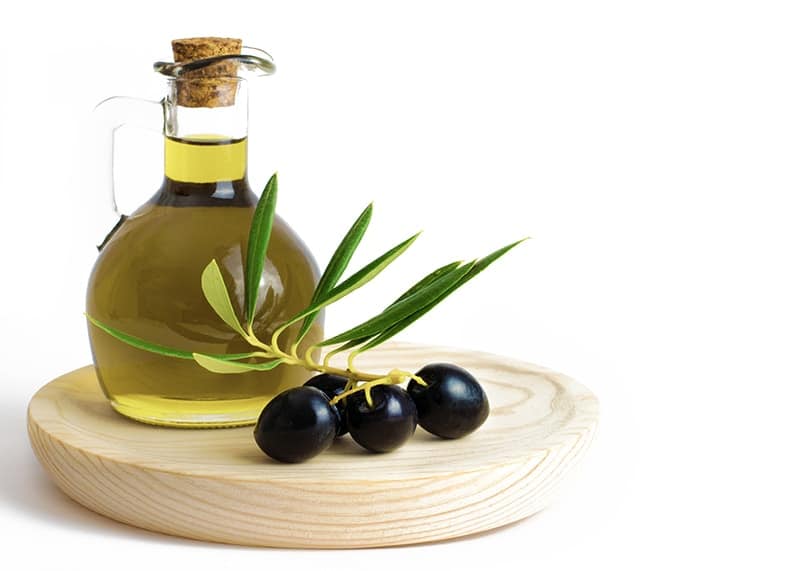a bottle of olive oil with fresh olives on the side