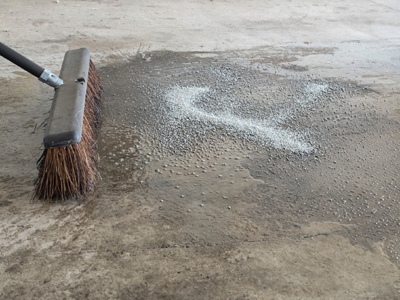 a broom and water cleans up an oil spill