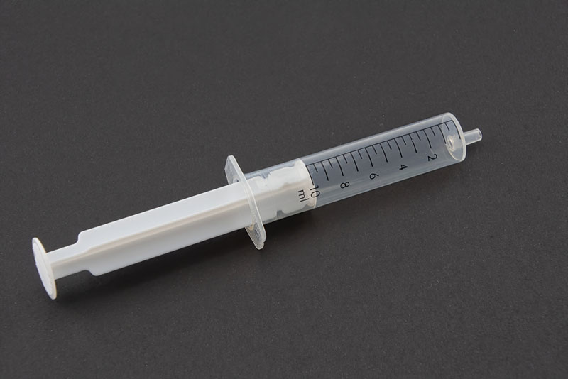 a clear plastic syringe on a black background