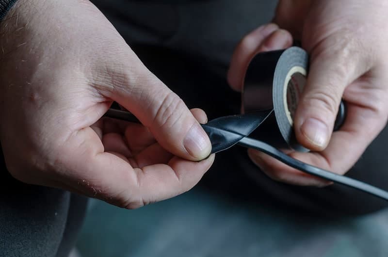 a man is insulating a black electrical wire