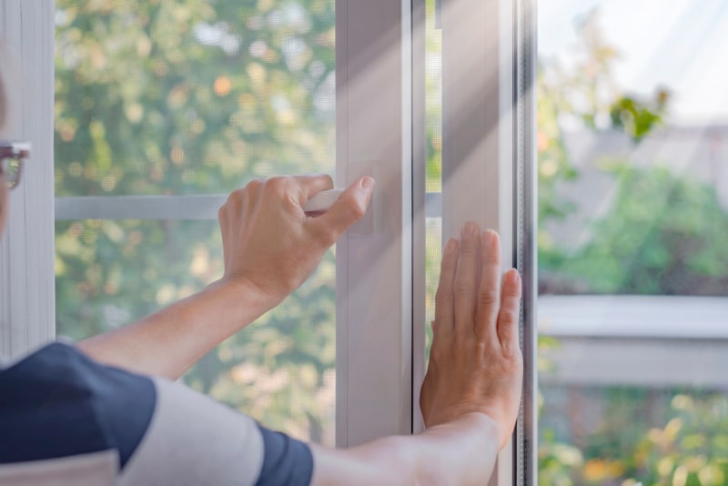 a woman closes a window in a room