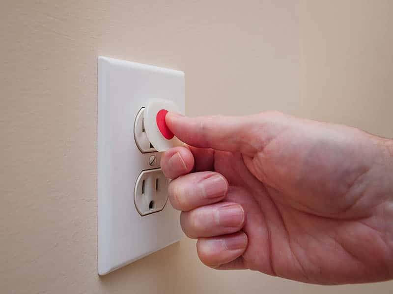 hand putting safety cover on outlet