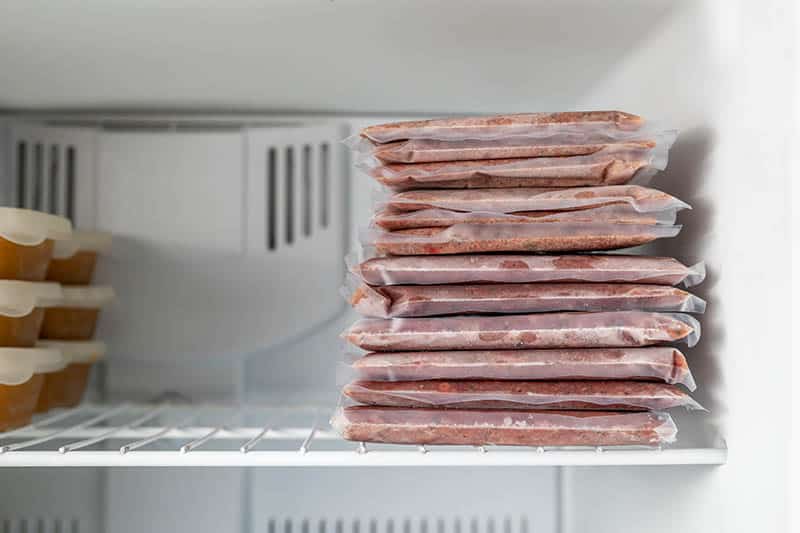 homemade cat food placed in vacuum bags and containers in the freezer