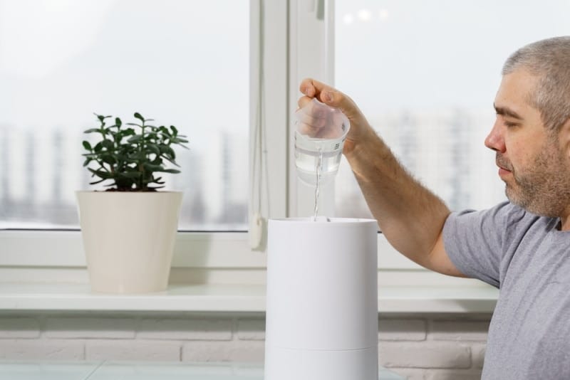man pouring water into humidifier