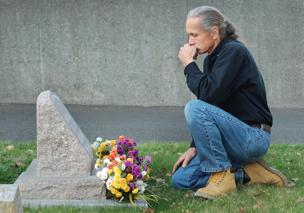 man sitting at grave site