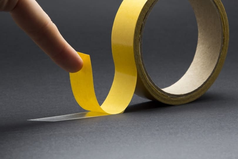 man's finger touches double sided tape