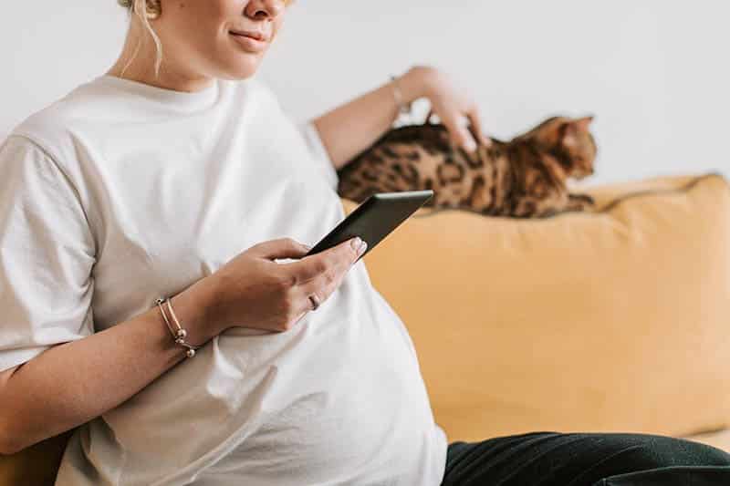 pergnant woman with cat using smartphone