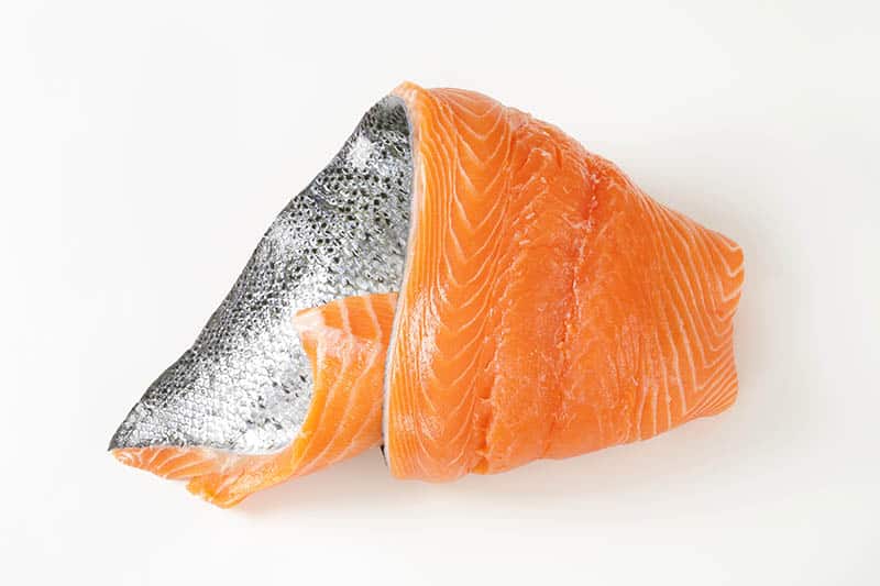 raw salmon fillet with silver skin on white background