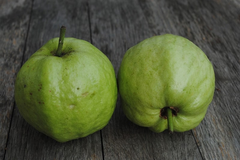 two guava fruits on wooden table
