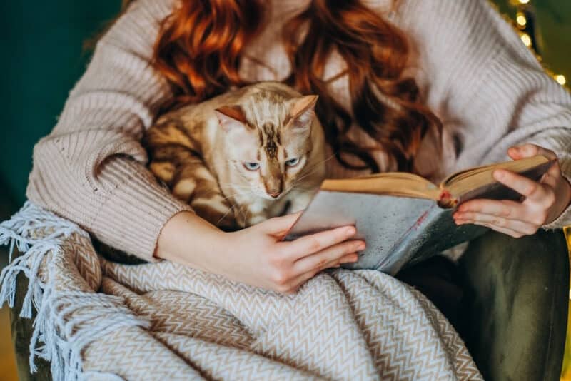 woman holding book and cat